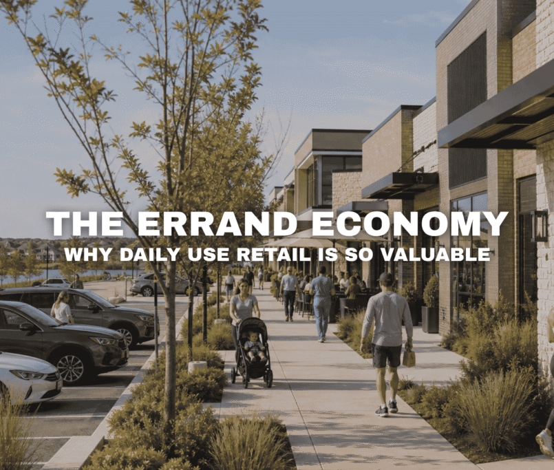Street-level view of Kettlestone Lakes in Waukee with active storefronts, parked cars, pedestrians, landscaped sidewalks, and a walkable daily-use retail environment near the lake.