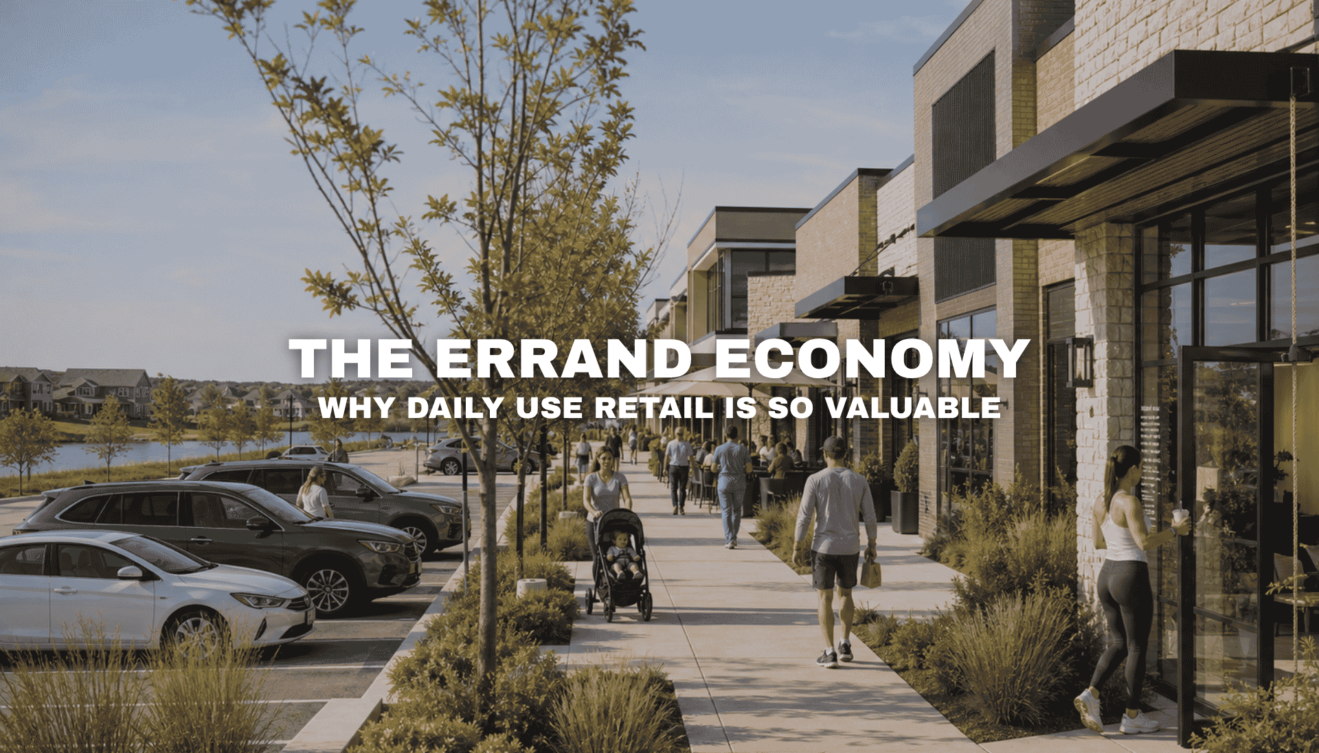 Street-level view of Kettlestone Lakes in Waukee with active storefronts, parked cars, pedestrians, landscaped sidewalks, and a walkable daily-use retail environment near the lake.