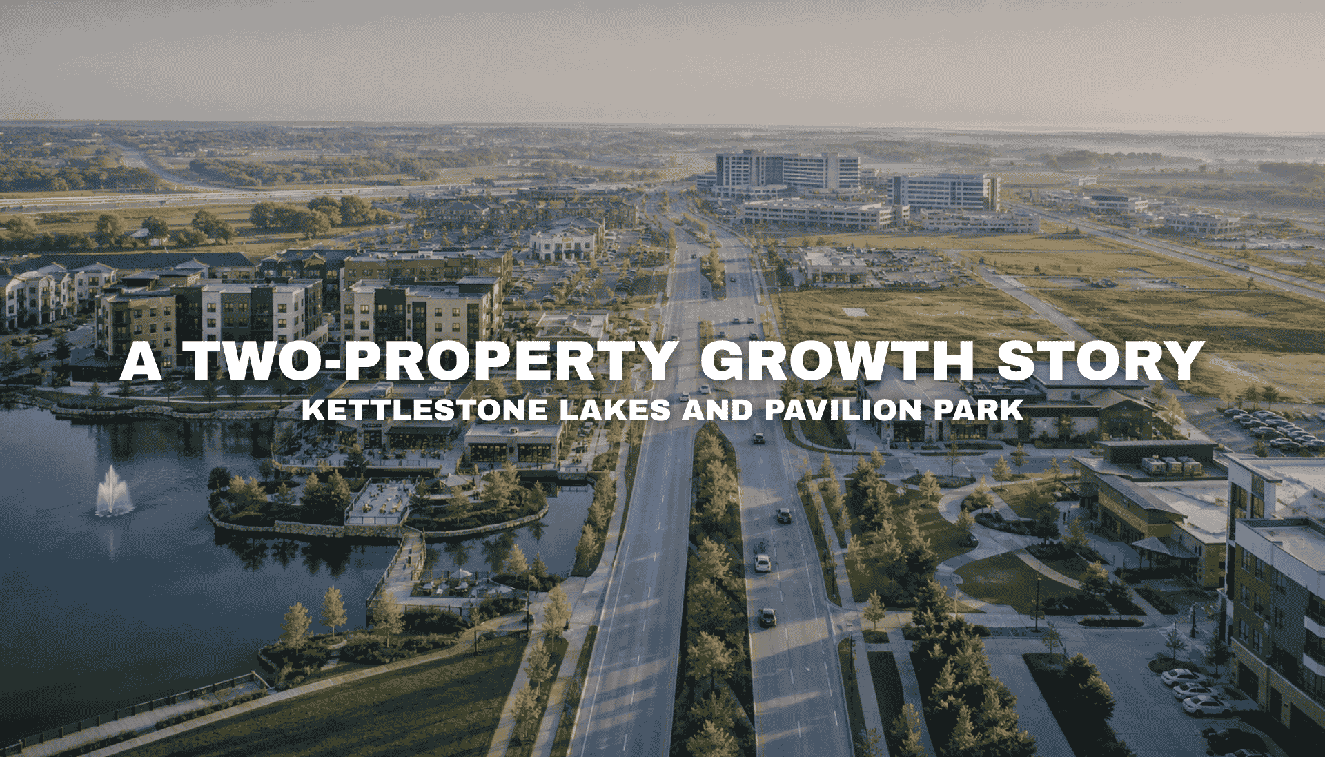 Aerial view of the Grand Prairie Parkway corridor with mixed-use development, lakeside buildings, broad roads, open parcels, and visible commercial growth connecting Waukee and West Des Moines.