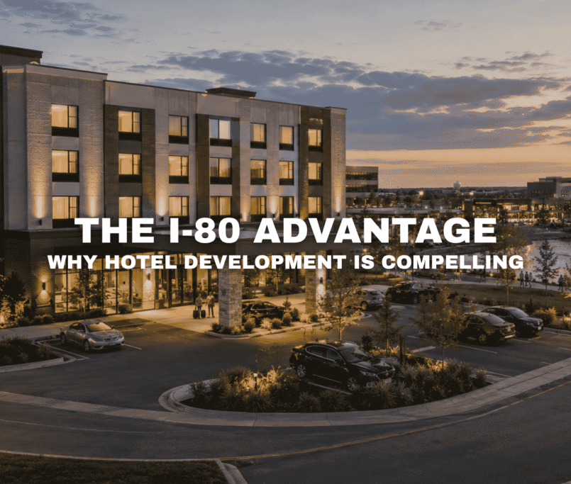 Modern hotel at Kettlestone Lakes in Waukee, Iowa with warm evening lighting, lakefront views, landscaped parking, walking paths, and nearby mixed-use commercial buildings.